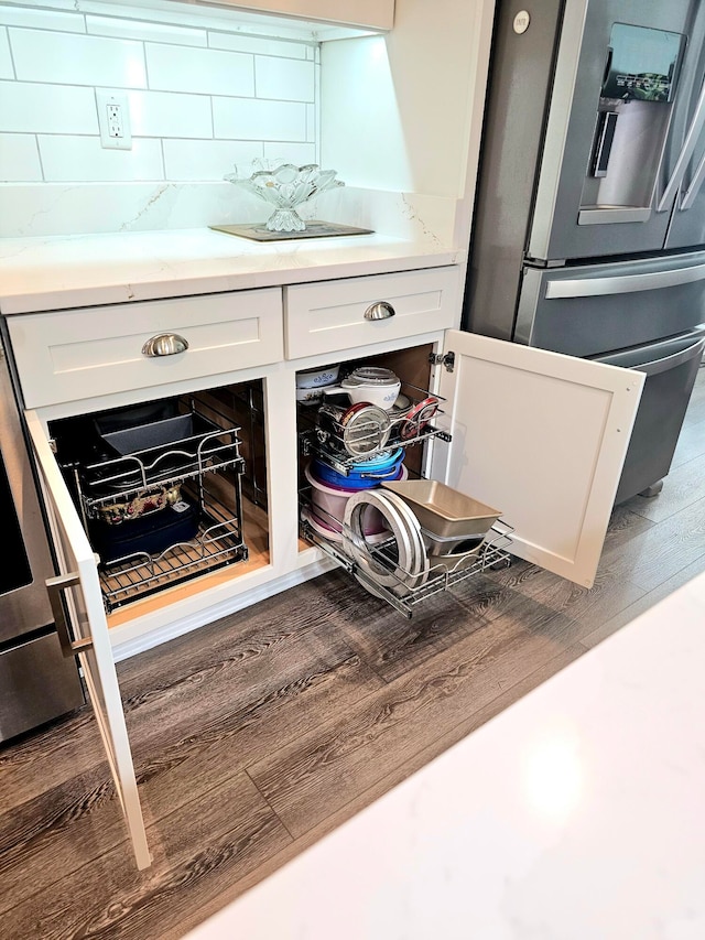 interior details with dark wood-type flooring, tasteful backsplash, white cabinetry, and stainless steel fridge