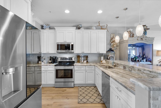 kitchen with a sink, stainless steel appliances, light wood-type flooring, crown molding, and a peninsula