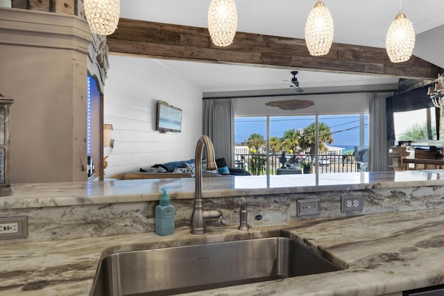 kitchen featuring hanging light fixtures, ornamental molding, beamed ceiling, and a sink