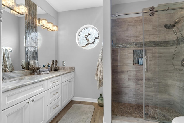 full bathroom with wood finished floors, vanity, and a stall shower
