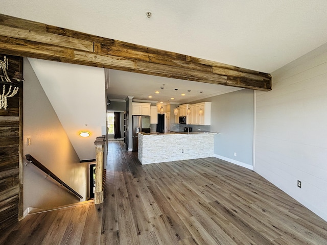 kitchen with white cabinets, stainless steel appliances, beam ceiling, dark wood finished floors, and a peninsula