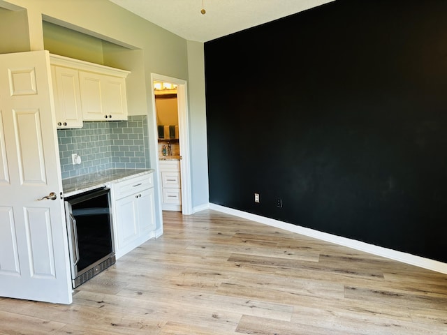 kitchen featuring white cabinets, backsplash, light wood-style flooring, and wine cooler