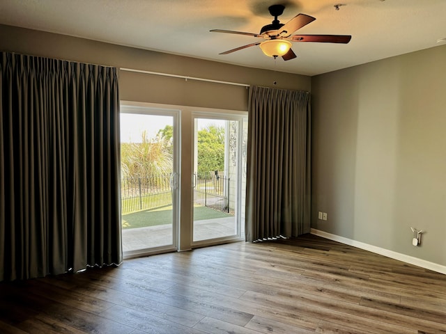 unfurnished room with a ceiling fan, baseboards, and wood-type flooring