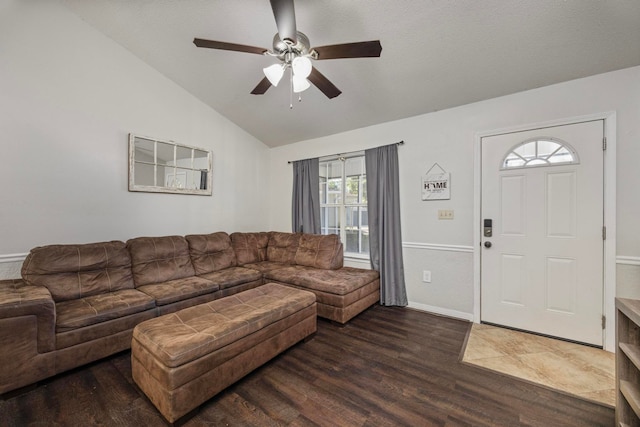 living room with ceiling fan, dark wood-type flooring, and vaulted ceiling