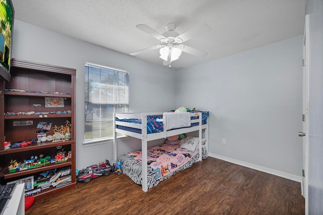 bedroom with ceiling fan, dark wood-type flooring, and a textured ceiling