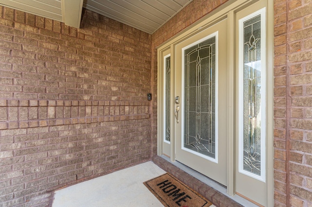 doorway to property with covered porch and brick siding