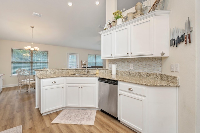 kitchen with stainless steel dishwasher, a peninsula, white cabinets, a sink, and light wood finished floors