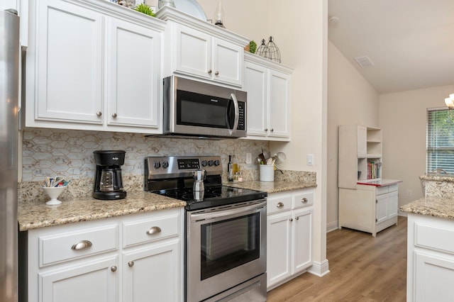 kitchen featuring decorative backsplash, visible vents, appliances with stainless steel finishes, white cabinetry, and light wood-style flooring