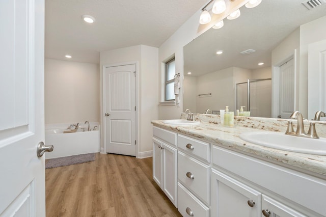 bathroom with vanity, hardwood / wood-style flooring, and plus walk in shower