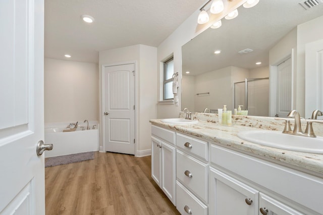 bathroom featuring a sink, a stall shower, wood finished floors, and visible vents