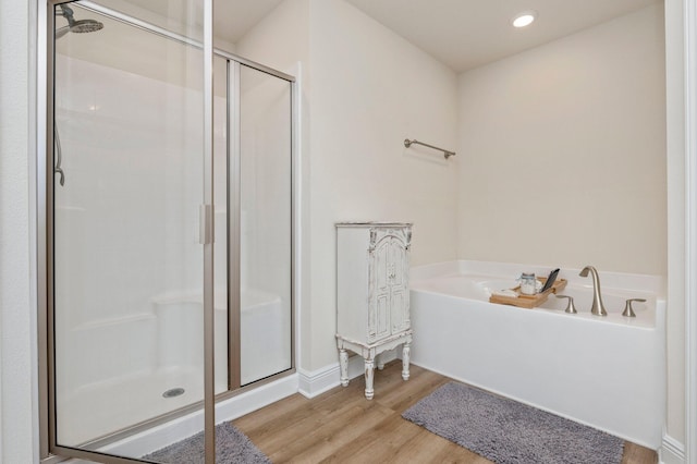full bathroom featuring a bath, a shower stall, wood finished floors, baseboards, and recessed lighting