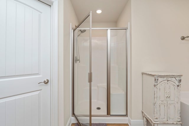 full bathroom featuring baseboards, a washtub, and a shower stall