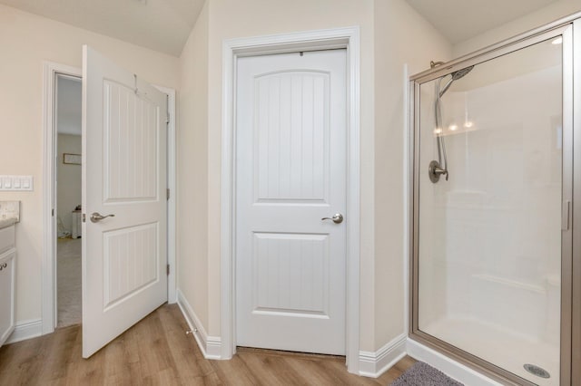 full bathroom with baseboards, a shower stall, wood finished floors, and vanity