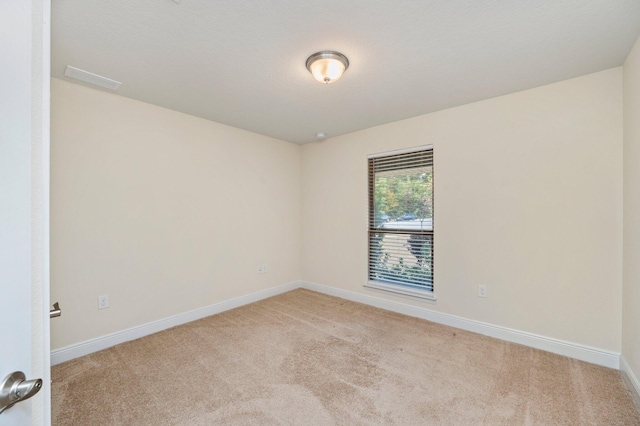 unfurnished room featuring baseboards, visible vents, and light carpet