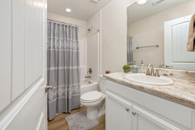 full bathroom with toilet, shower / tub combo, hardwood / wood-style floors, vanity, and a textured ceiling