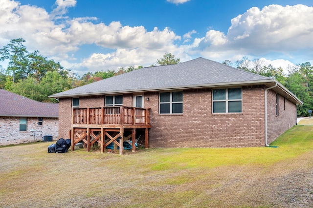 back of property with a lawn, brick siding, a wooden deck, and a shingled roof