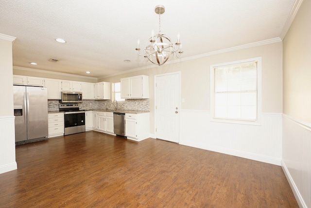 kitchen with dark wood-type flooring, white cabinets, stainless steel appliances, and decorative light fixtures