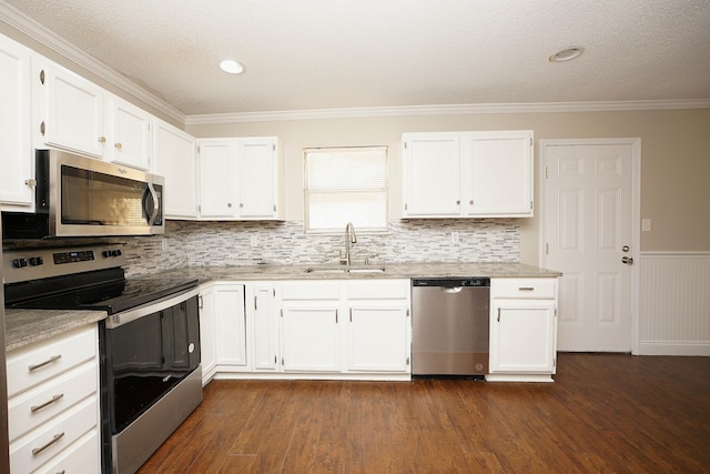 kitchen with appliances with stainless steel finishes, dark hardwood / wood-style flooring, white cabinetry, and sink