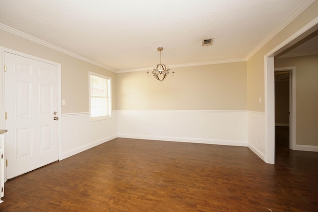 spare room with a textured ceiling, crown molding, dark wood-type flooring, and a notable chandelier