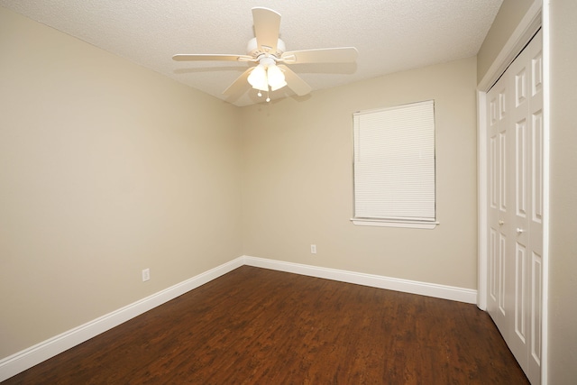 empty room with ceiling fan, dark hardwood / wood-style flooring, and a textured ceiling