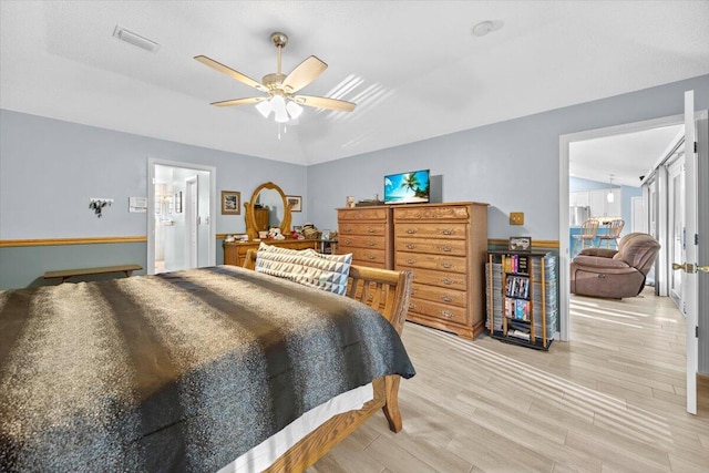 bedroom with ceiling fan, connected bathroom, light wood-type flooring, and lofted ceiling