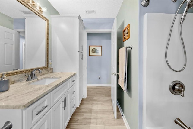 bathroom with a textured ceiling, vanity, and hardwood / wood-style flooring