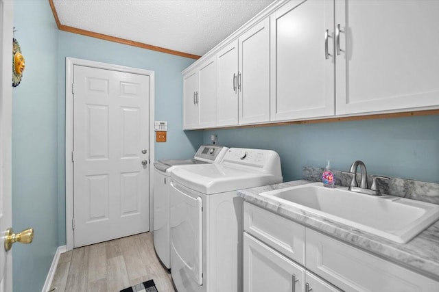 washroom featuring ornamental molding, light wood-type flooring, a textured ceiling, cabinets, and independent washer and dryer