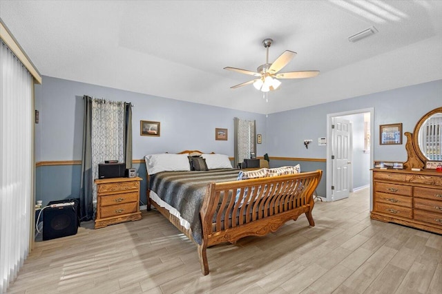 bedroom with ceiling fan, a textured ceiling, and light hardwood / wood-style flooring