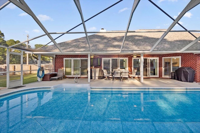 view of pool with a grill, glass enclosure, and a patio