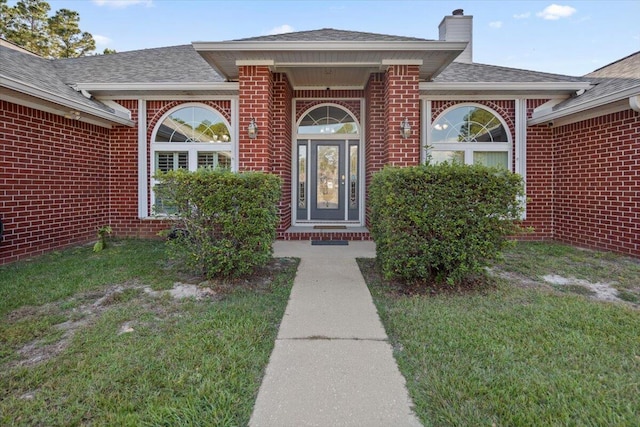 property entrance with a lawn