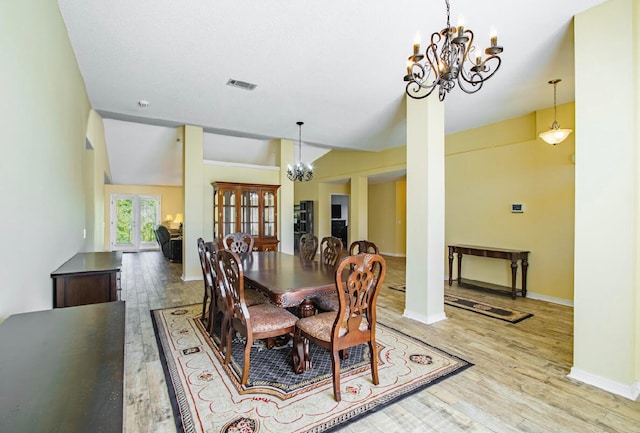 dining area featuring french doors, vaulted ceiling, a notable chandelier, and hardwood / wood-style flooring