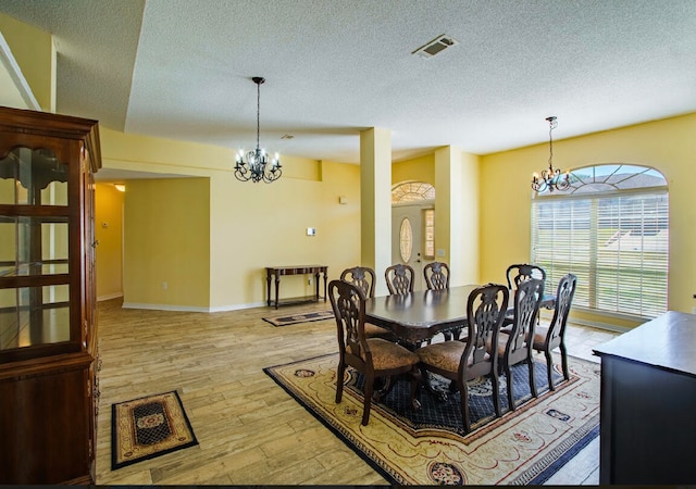 dining space featuring light hardwood / wood-style floors, a notable chandelier, and a textured ceiling