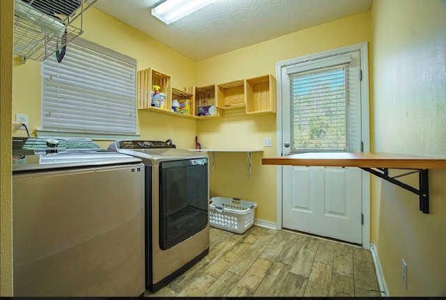 laundry area featuring separate washer and dryer, a textured ceiling, and light hardwood / wood-style floors