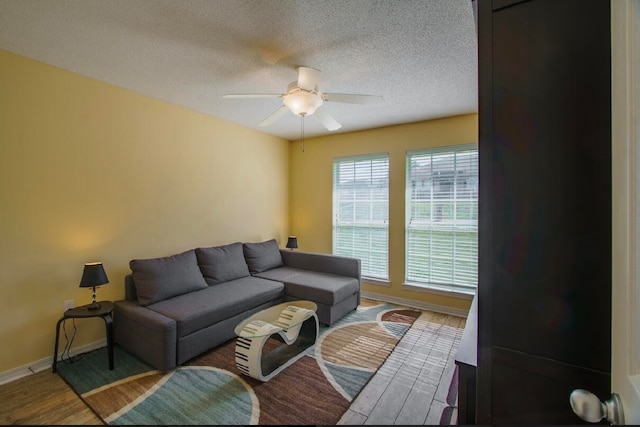 living room featuring a textured ceiling, wood-type flooring, and ceiling fan