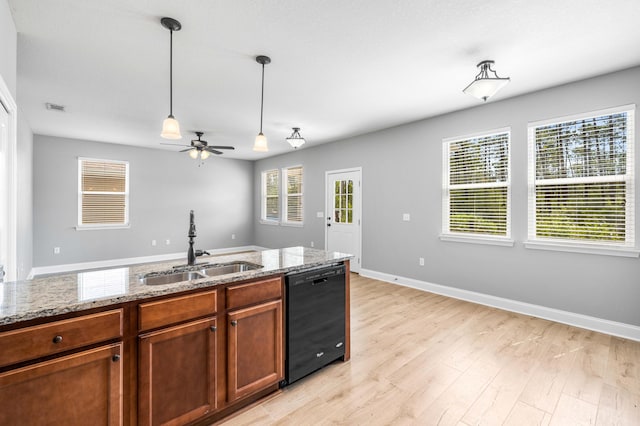 kitchen featuring black dishwasher, light hardwood / wood-style flooring, light stone counters, and a healthy amount of sunlight