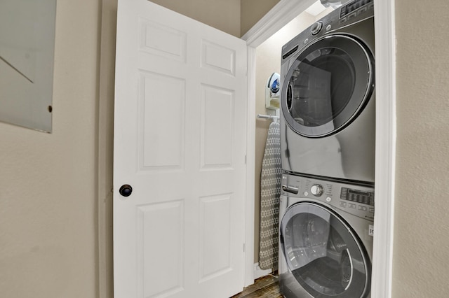 washroom featuring stacked washing maching and dryer and dark wood-type flooring