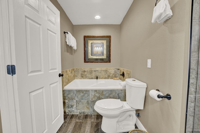 bathroom featuring hardwood / wood-style floors, toilet, and tiled bath