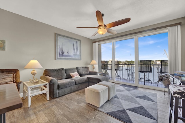 living room with hardwood / wood-style flooring, a water view, and ceiling fan