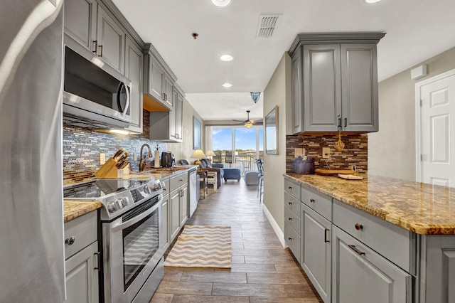 kitchen featuring backsplash, stainless steel appliances, dark hardwood / wood-style flooring, and gray cabinets