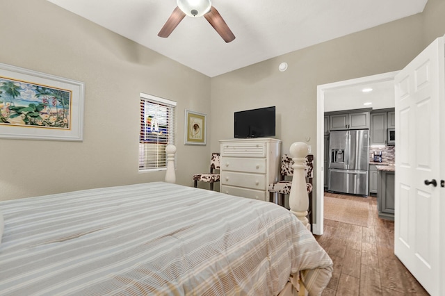 bedroom with hardwood / wood-style floors, ceiling fan, and stainless steel fridge with ice dispenser