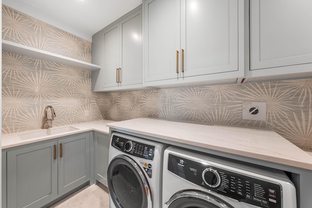 laundry area with washing machine and clothes dryer, cabinet space, and a sink