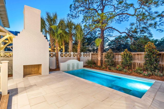 view of swimming pool featuring an outdoor brick fireplace and a patio area