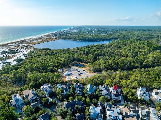 drone / aerial view featuring a wooded view, a water view, and a residential view