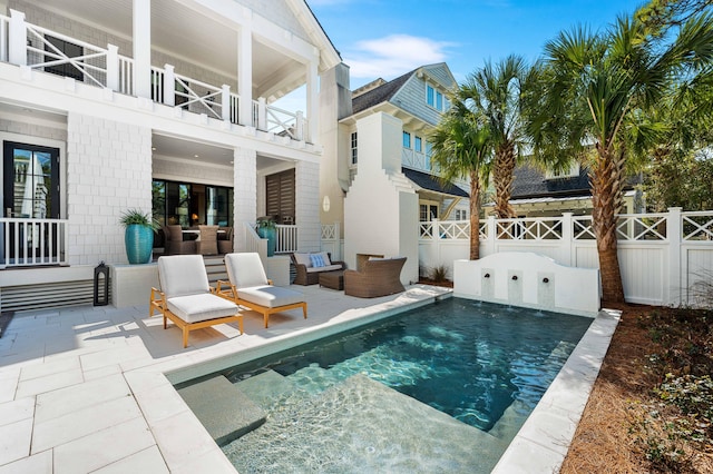 rear view of property featuring an outdoor living space, a balcony, a patio area, and a fenced backyard