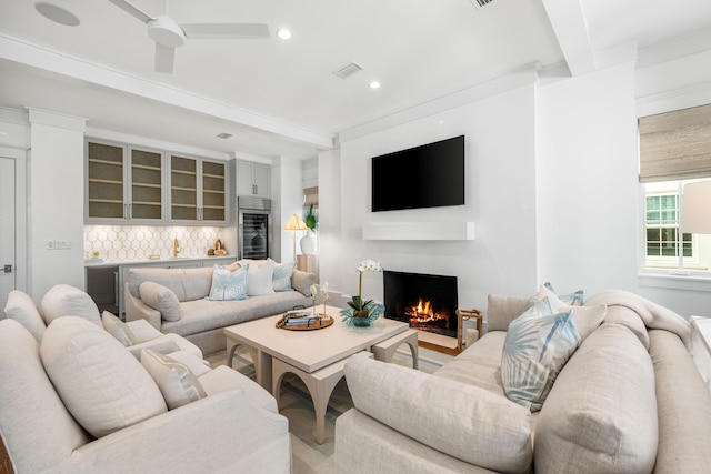 living room featuring visible vents, ceiling fan, beam ceiling, recessed lighting, and a warm lit fireplace