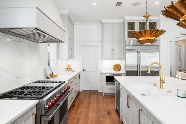 kitchen featuring visible vents, dark wood-type flooring, custom range hood, a sink, and high end appliances