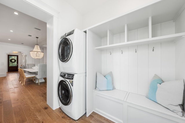 laundry room with laundry area, recessed lighting, stacked washer and clothes dryer, and hardwood / wood-style floors