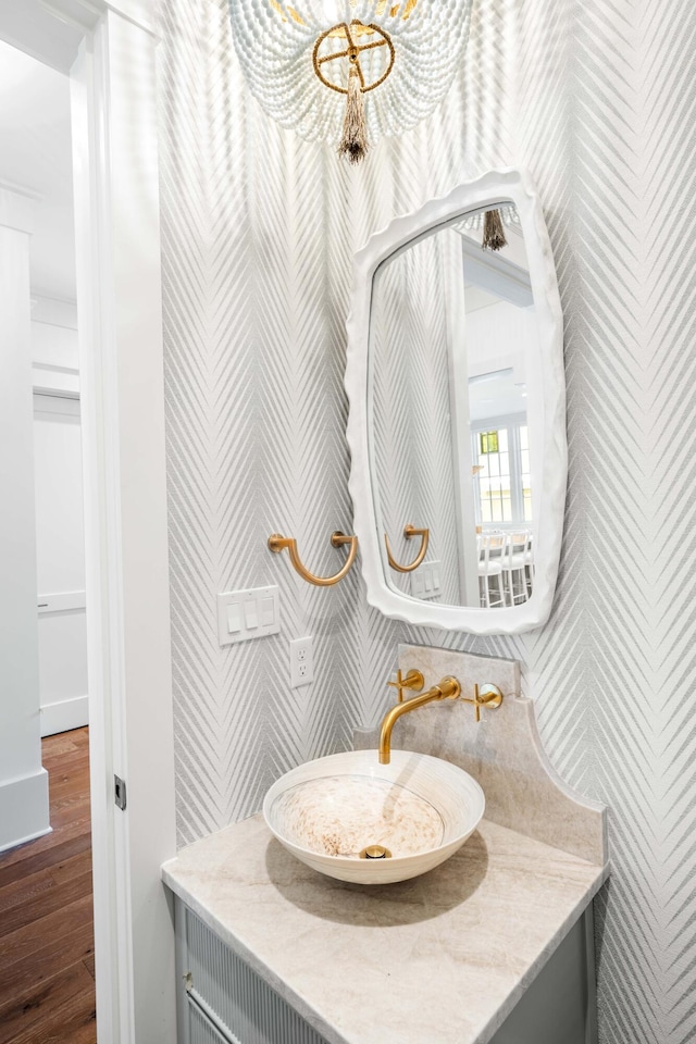 bathroom with a notable chandelier, wood finished floors, and vanity