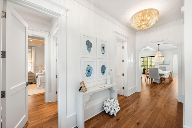 hall featuring a chandelier, ornamental molding, and hardwood / wood-style flooring