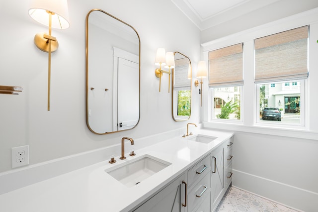 bathroom with a sink, baseboards, double vanity, and crown molding